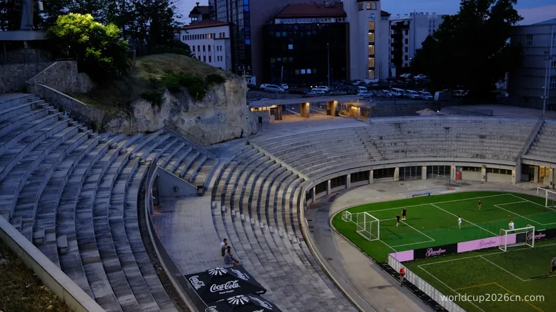 Football stadium with tiered seating and city buildings at dusk.