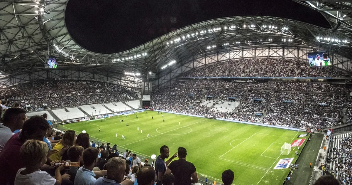 Wide shot of a football stadium south stand with waving flags, passionate football fans in