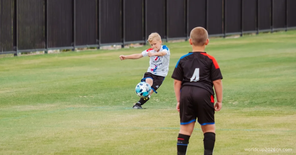 2 boys playing soccer on green grass field during daytime