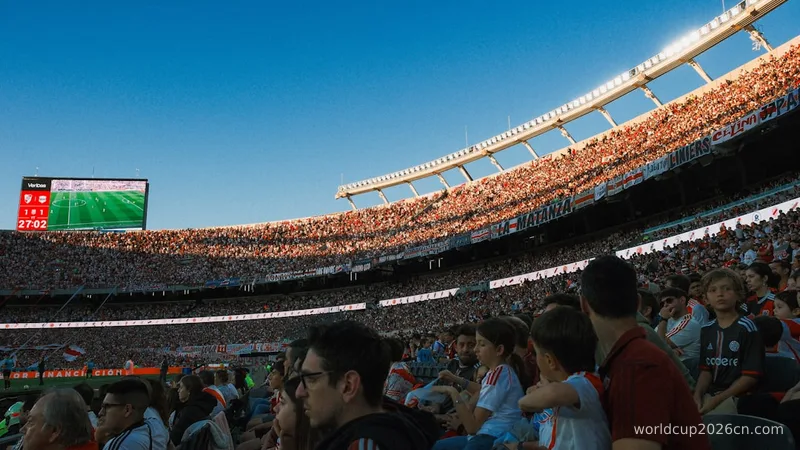 Crowded stadium watching a soccer game under clear sky.