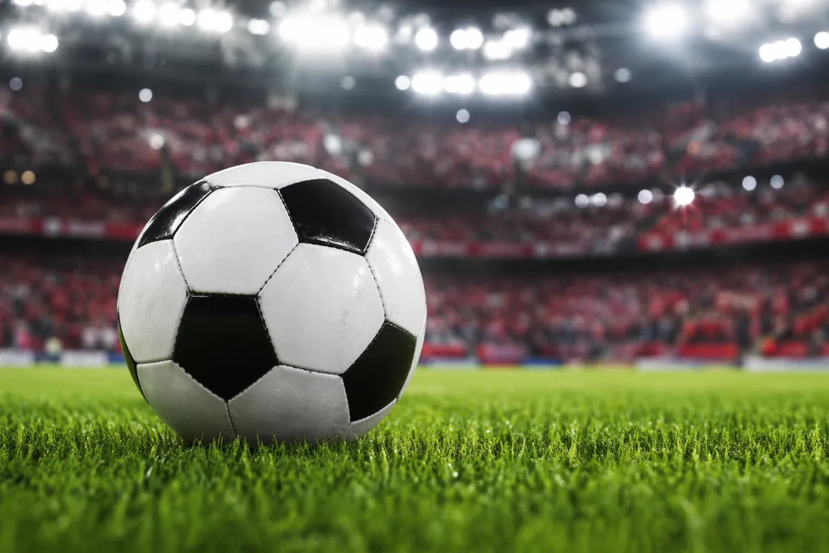 Close-up shot of a generic unbranded soccer ball resting on a lush green professional foot