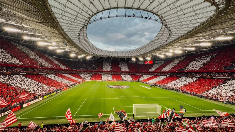 A packed stadium with red and white supporters cheering fans.
