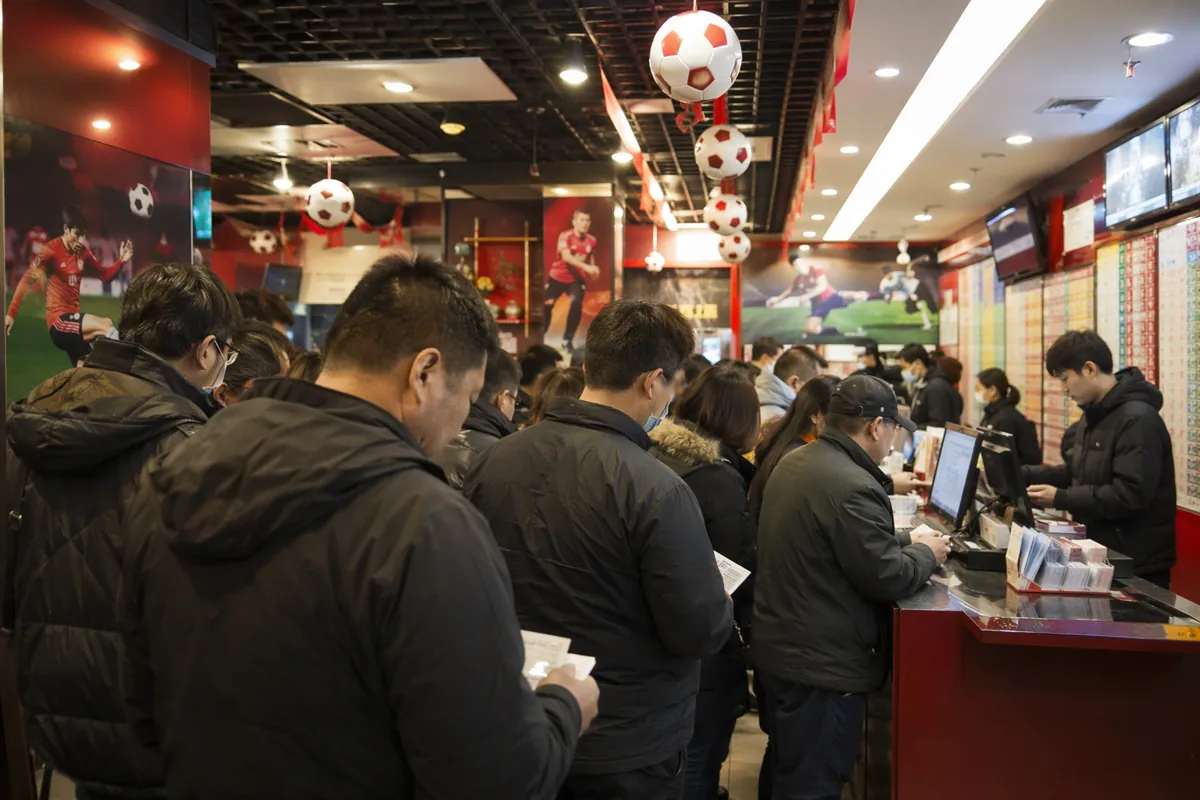 Wide shot of a crowded official sports lottery shop in China, fans lining up to buy ticket