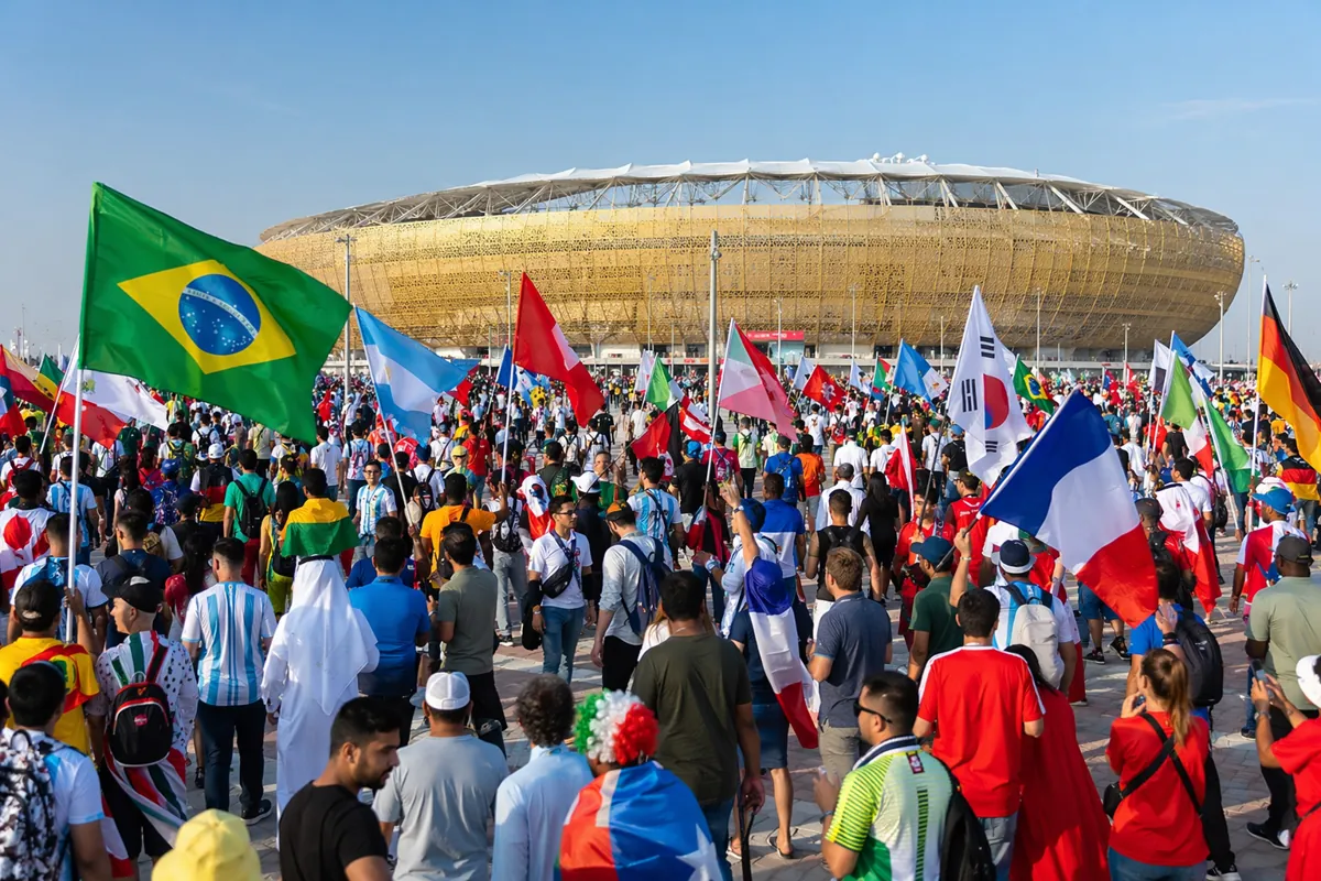Wide shot of a crowded World Cup football stadium entrance with fans holding national flag