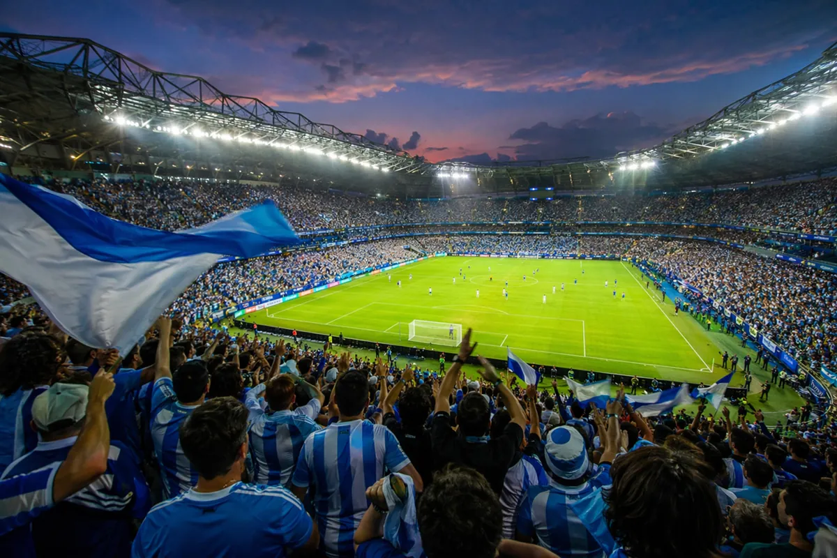 Wide shot of a packed world cup football stadium at dusk, bright stadium lights illuminati