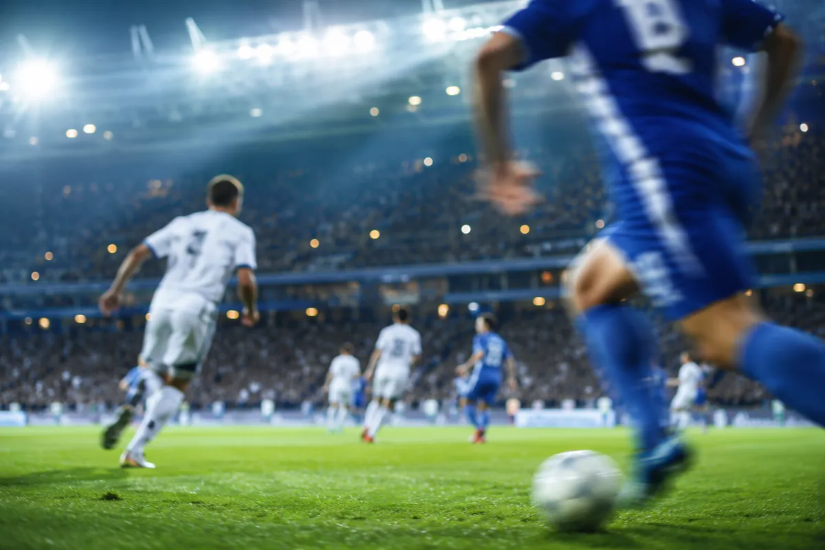 Professional sports news header image, blurred football match scene, blue and white team j