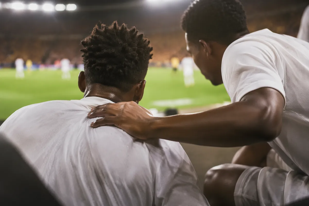 Editorial sports news header, blurred sideline of a professional football match, two playe