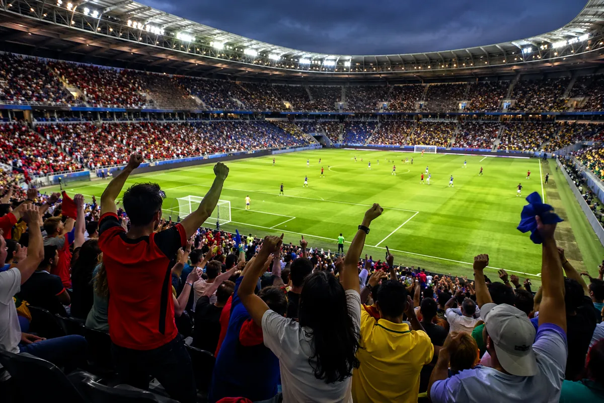 Wide shot of a vibrant international football stadium during a match, green grass pitch in