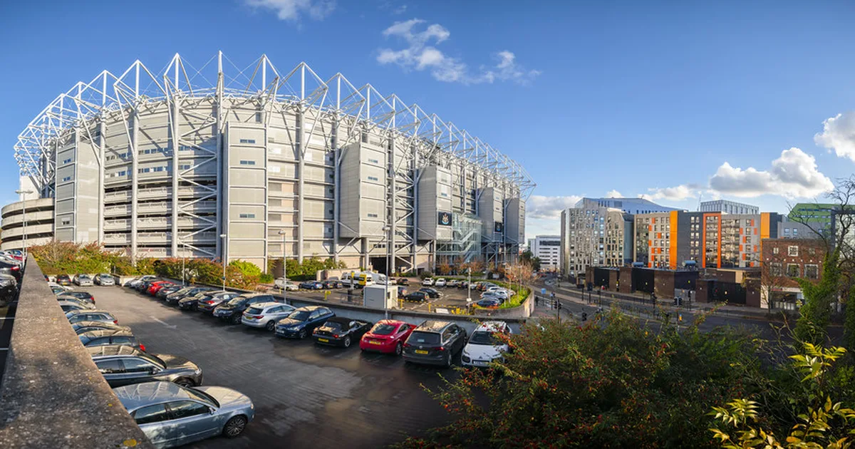 Wide shot of a generic international football stadium at golden hour, with blurred fans wa