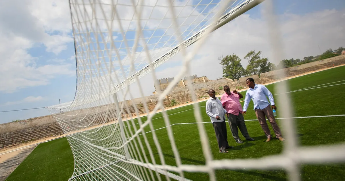 Wide shot of a modern football stadium stands during a friendly match, with blurred specta