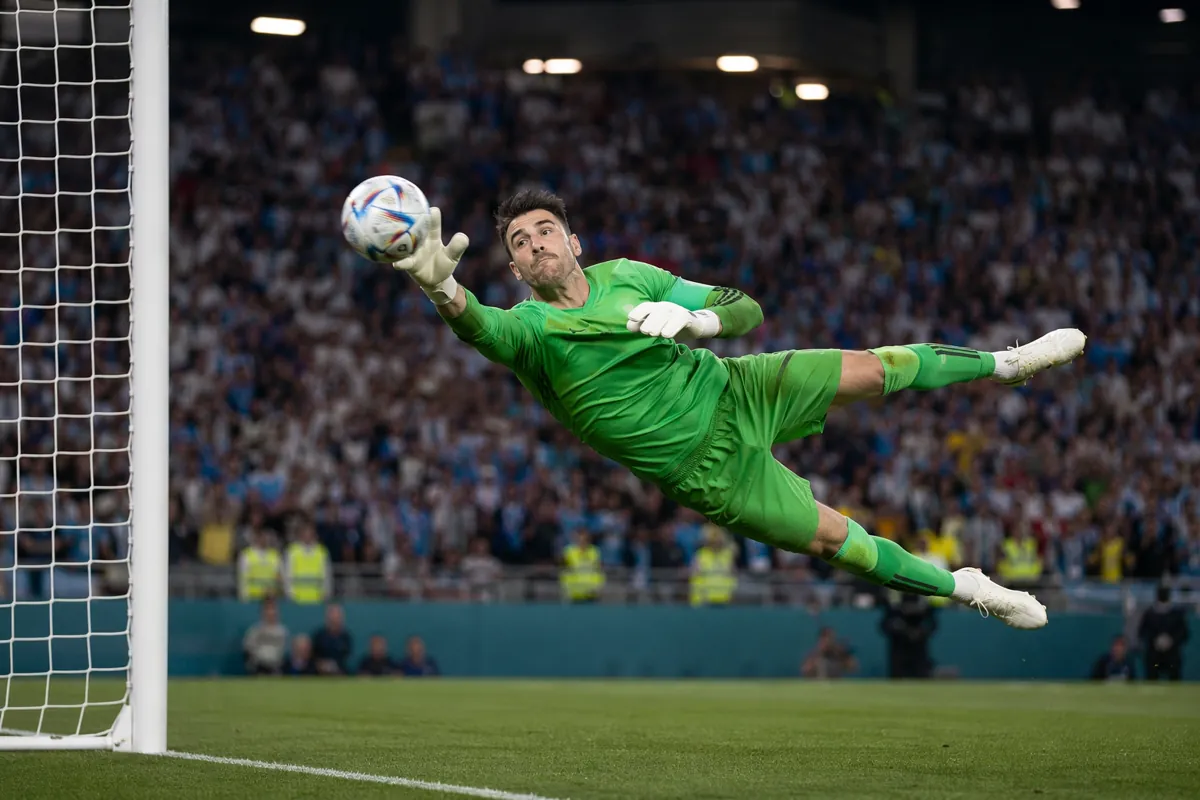 Professional sports photography, wide shot of a soccer goalkeeper making a diving save dur