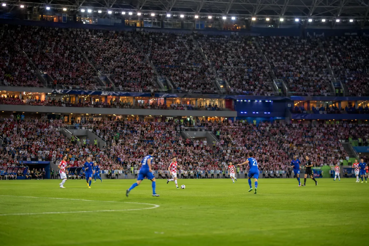 Wide shot of a professional football stadium during a World Cup match, blurred players in