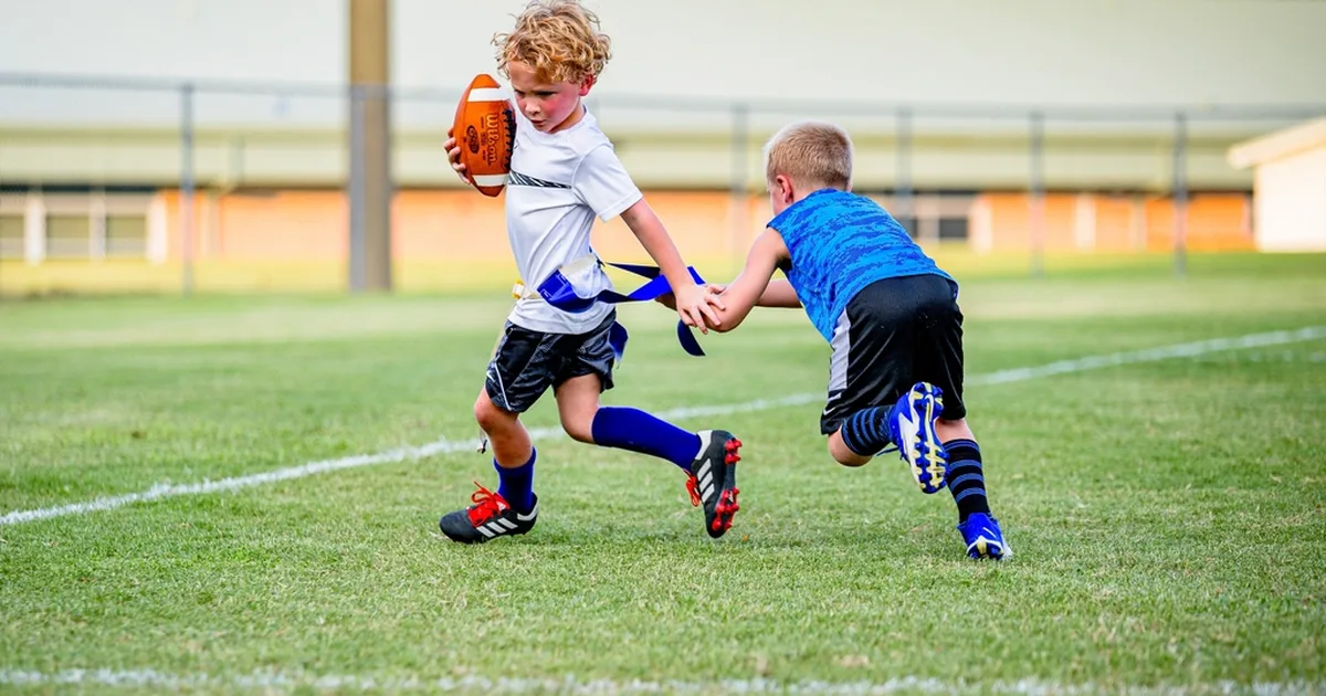 Wide shot of a professional football training ground, group of coaches and young players o
