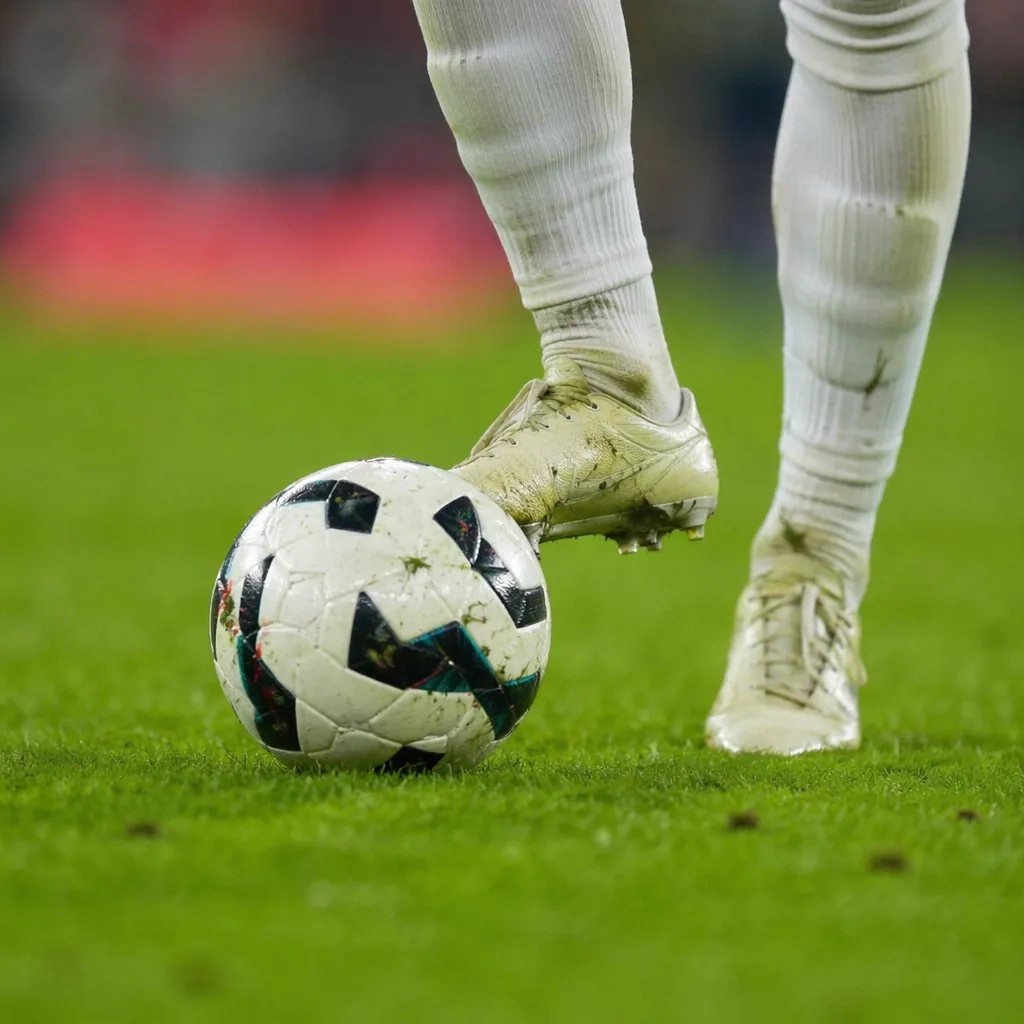 Close up shot of a generic football midfielder's boots and football on green pit
