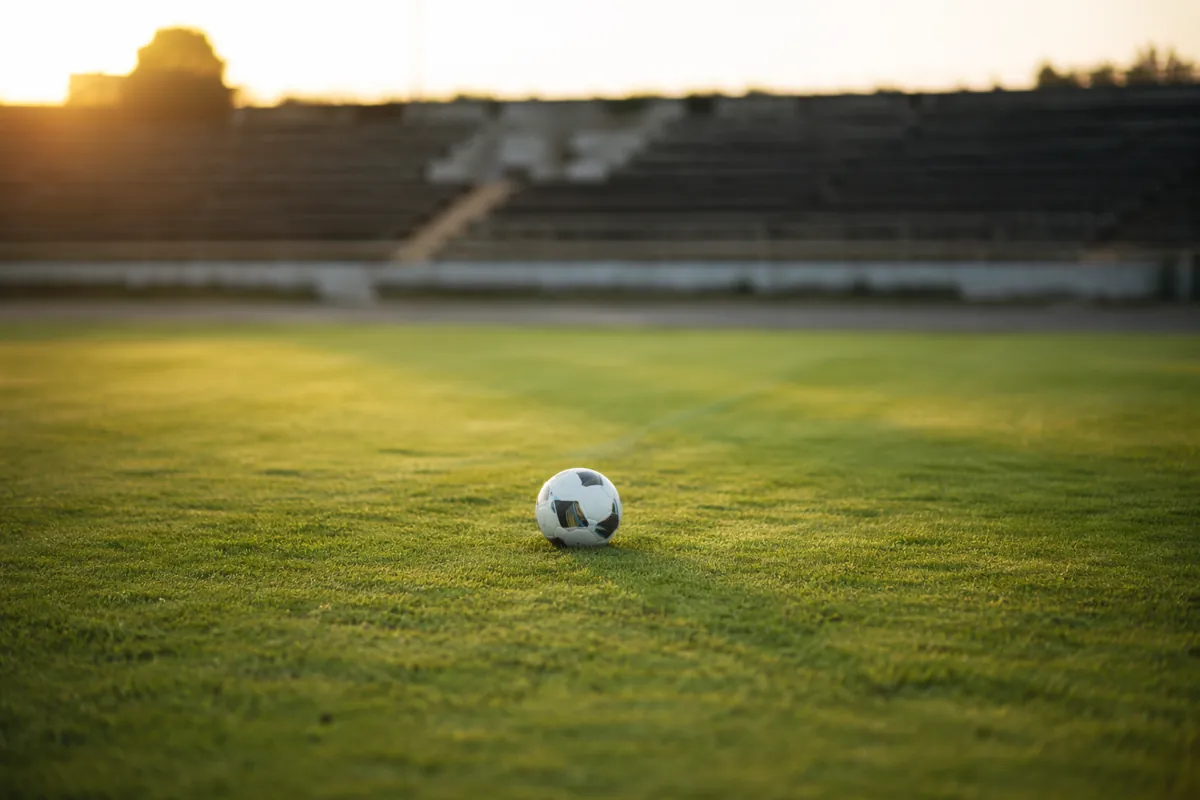 Photojournalistic shot of an empty green football training pitch with a single soccer ball