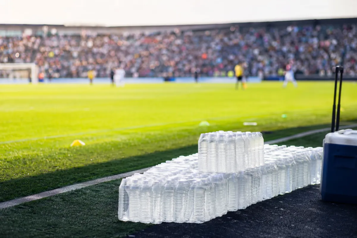 Professional editorial sports photograph of a soccer field sideline during a daytime break