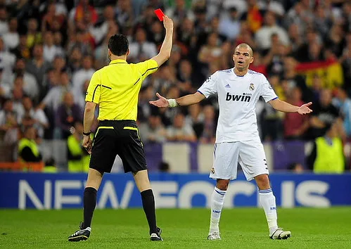 close up photo of a soccer referee holding a red card, blurred stadium backgroun