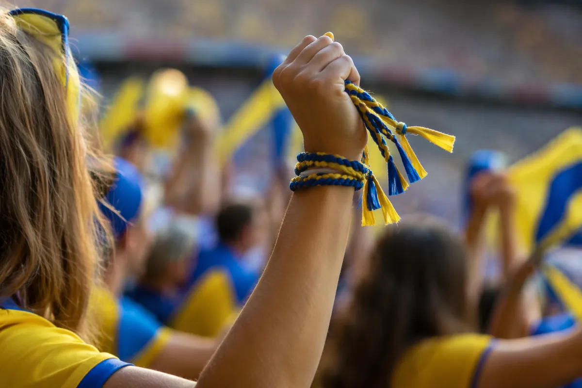 Vibrant World Cup fan atmosphere shot, colorful woven hair ties in yellow and blue held by