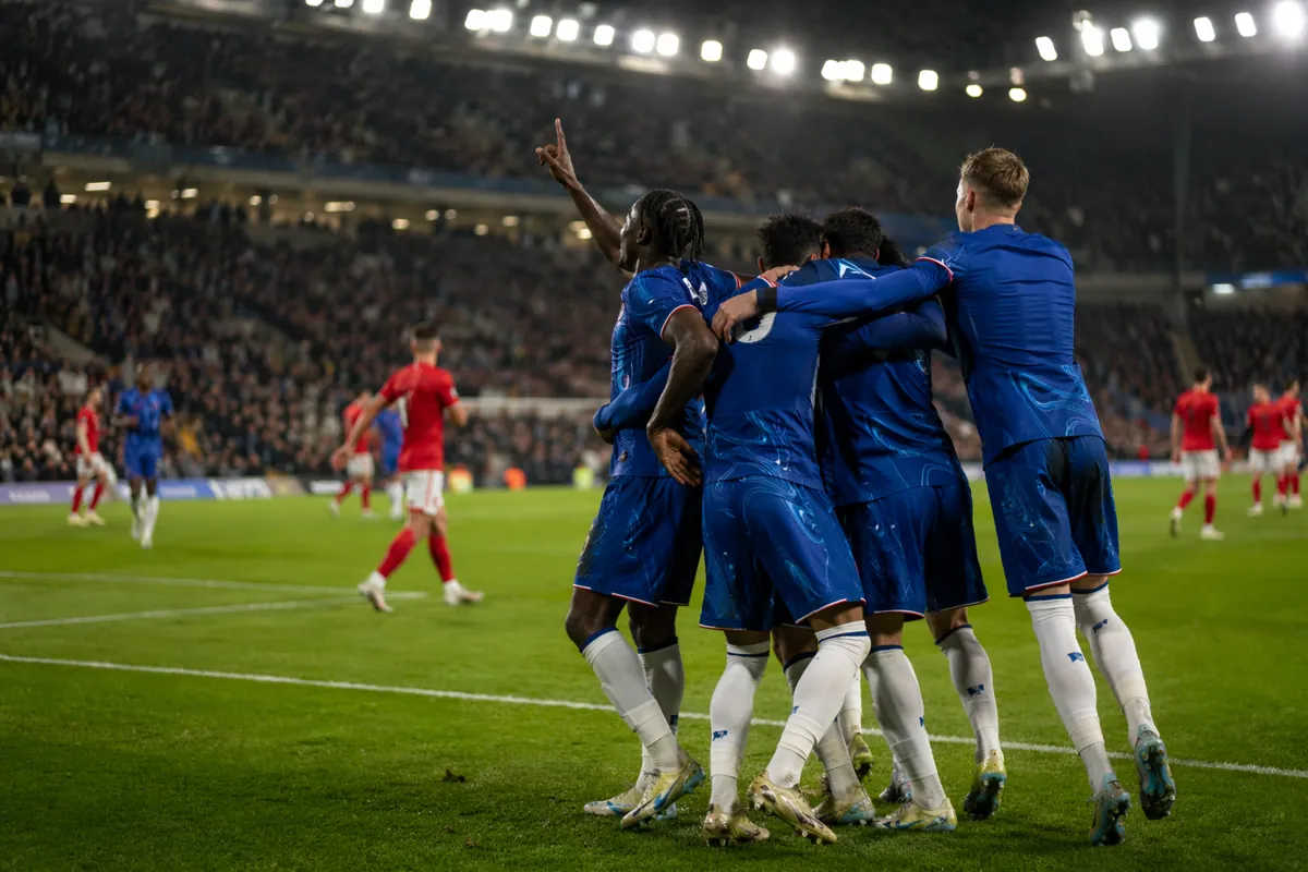Professional football match wide shot, bright stadium floodlights, blurred players in blue