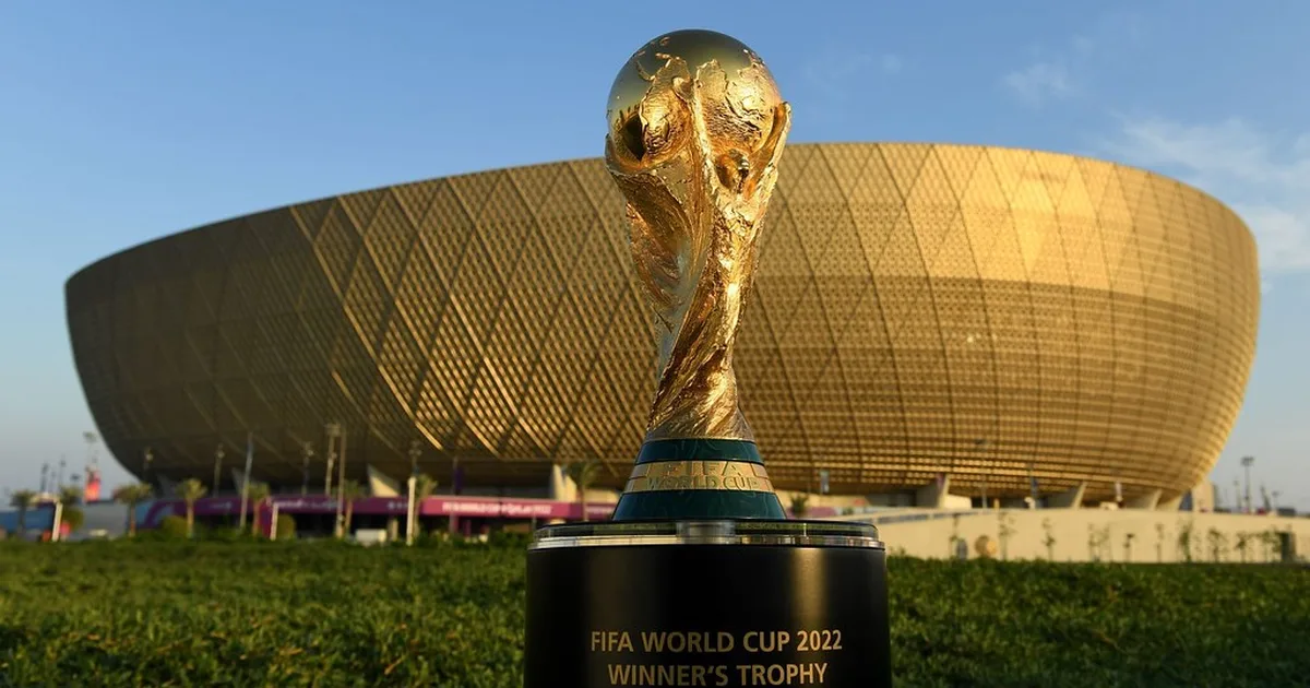 Professional editorial news photo of a golden FIFA World Cup trophy placed on a dark woode
