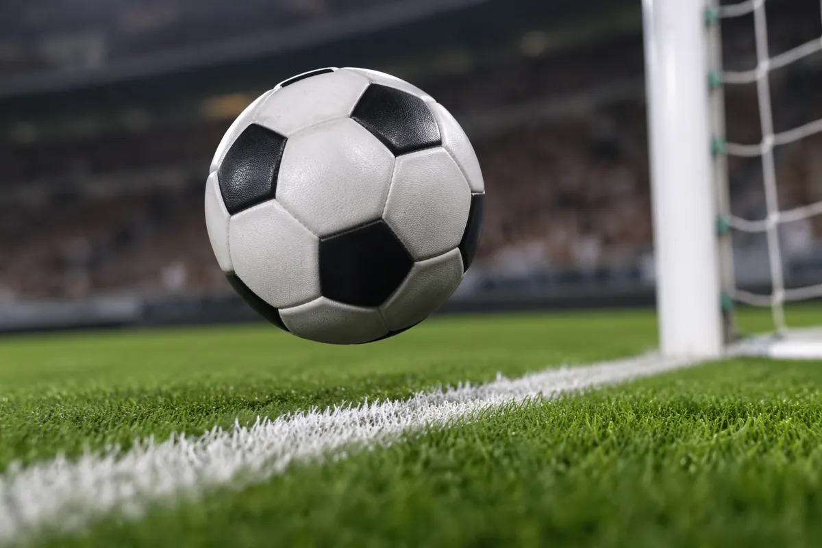 Close-up shot of a football hovering just above the white goal line of a professional socc