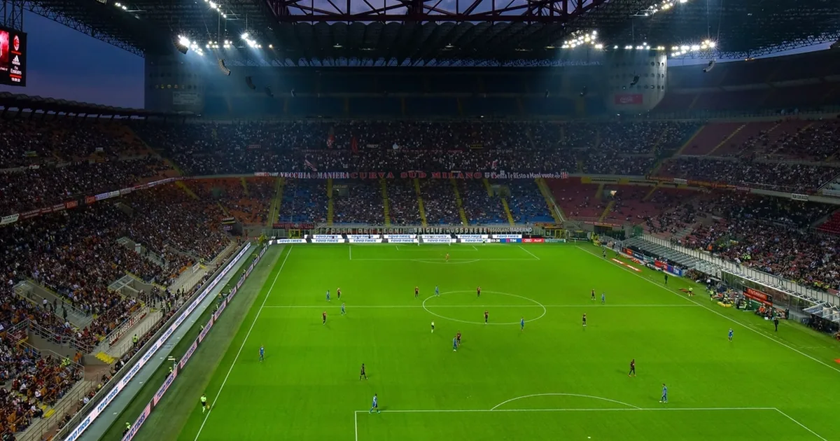 Editorial football transfer news header, blurred view of San Siro stadium turf with folded