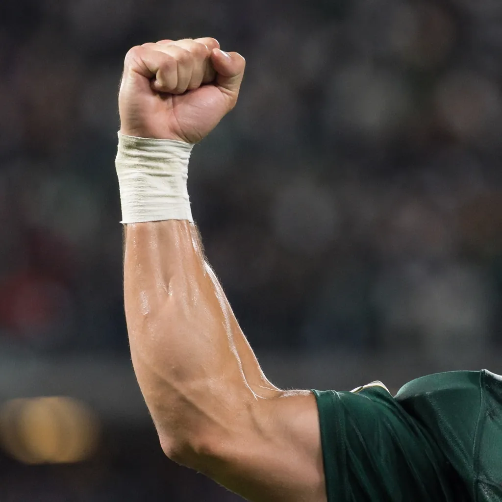 Close up shot of a football player's clenched fist punching the air in celebrati