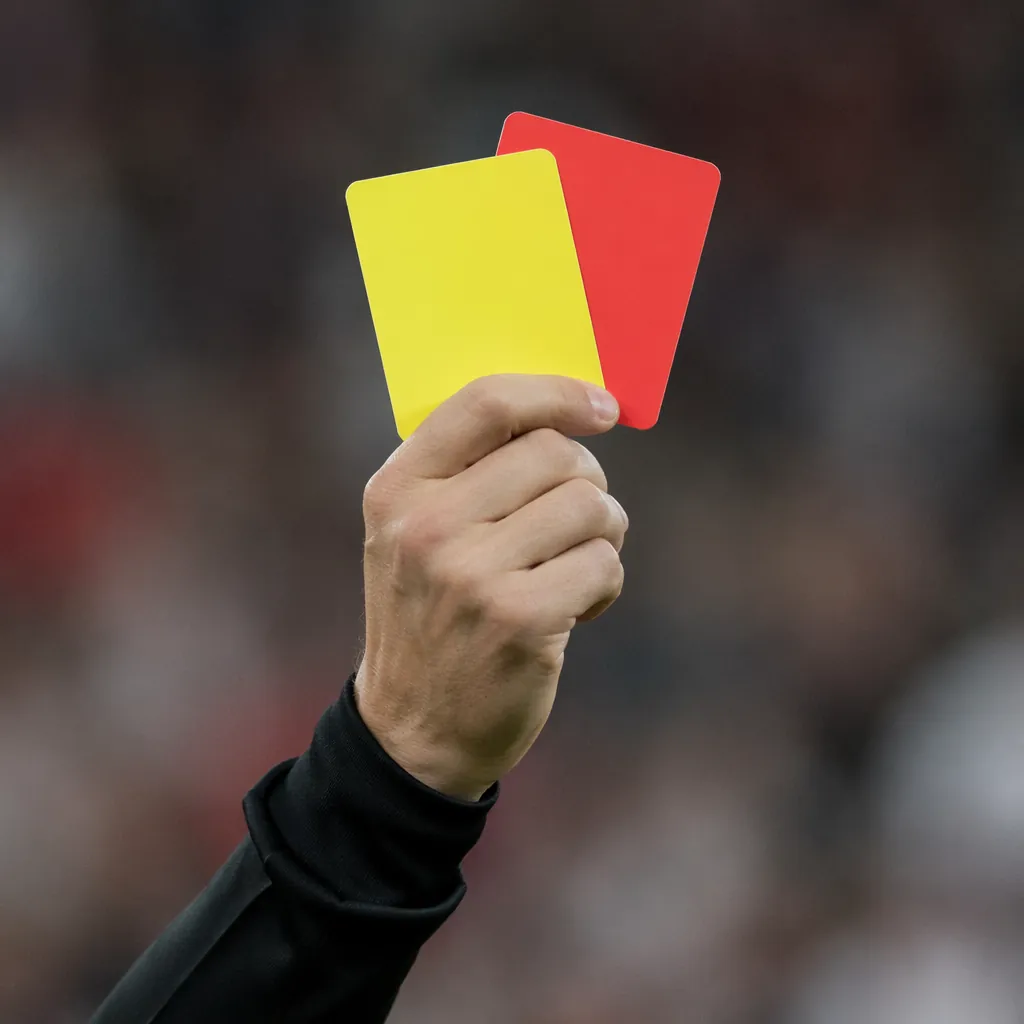 Close up of a referee's hand holding a yellow card and red card, black uniform s