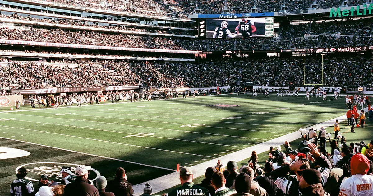 Wide shot of a modern professional football stadium at sunset, filled with cheering specta