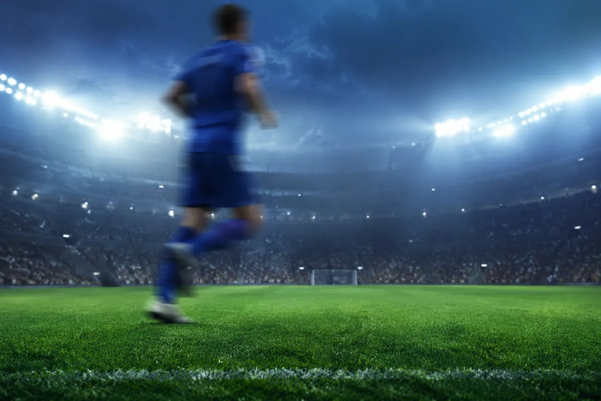 Professional sports news header image, blurred soccer player in blue jersey running on gre