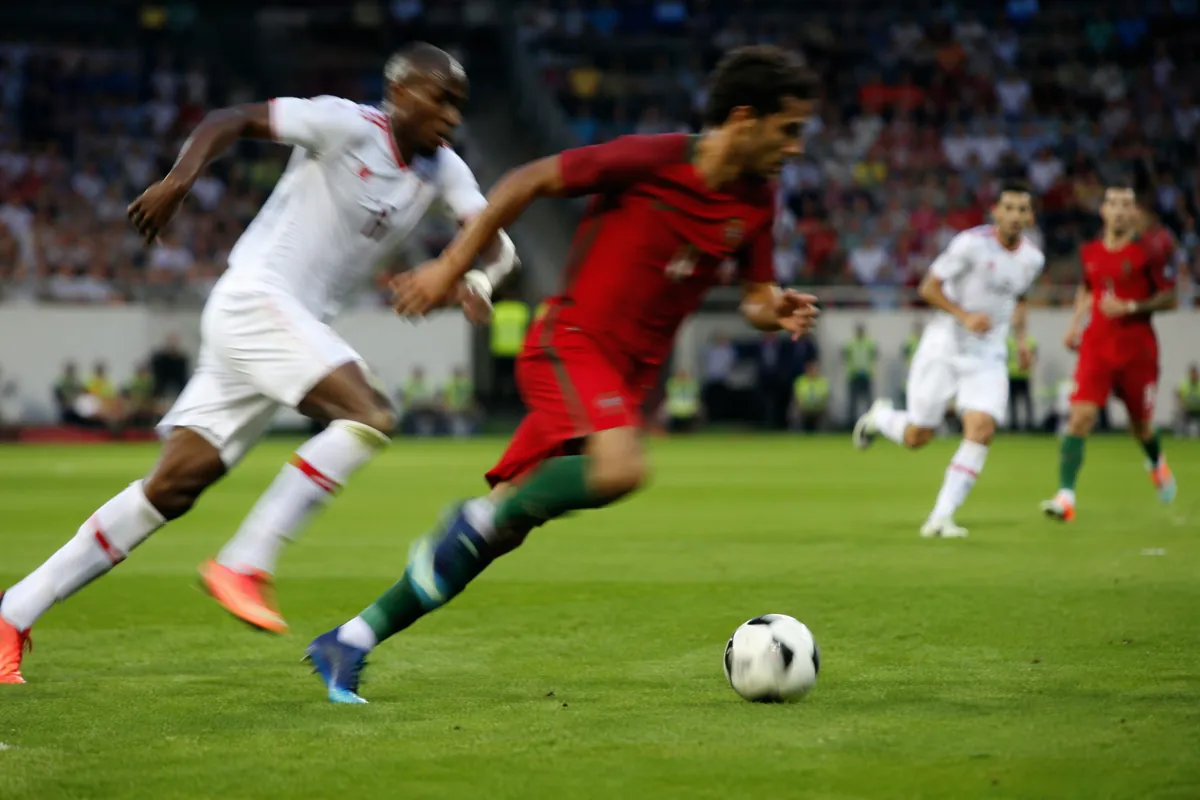 Professional sports news header image, wide shot of a green football pitch during a profes