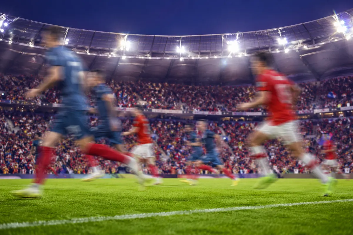 Editorial news header image for World Cup, blurred football players running on green pitch