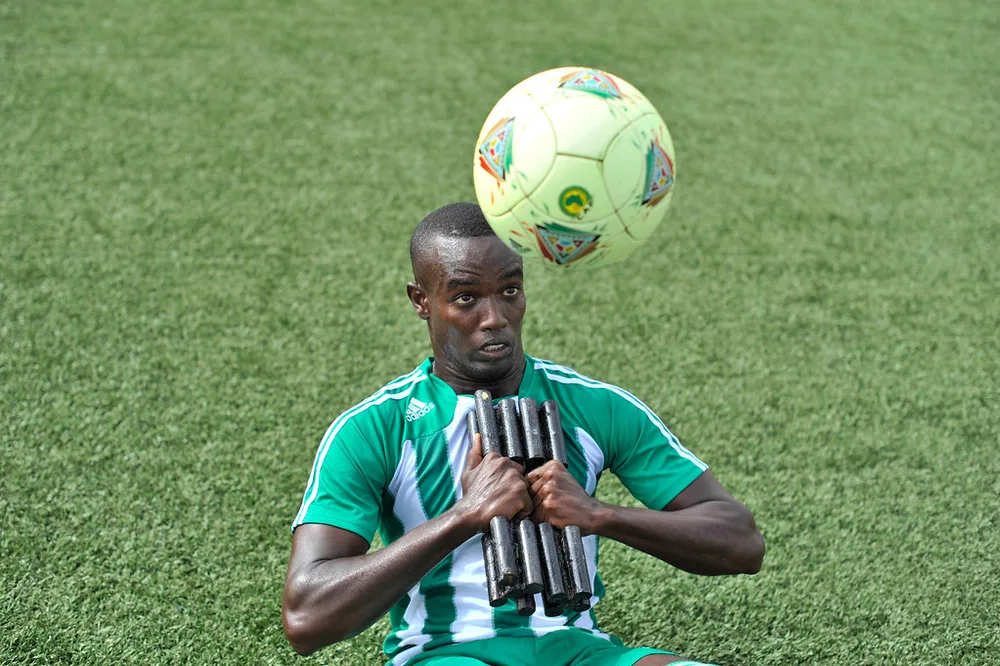 Football coach talking to a player on training pitch, soft focus, no recognizabl