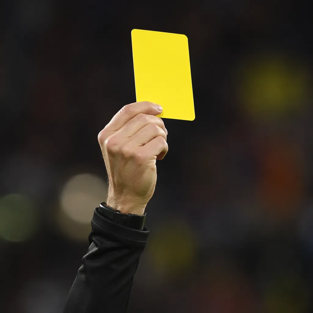Close up shot of a referee showing a yellow card during a football match, no vis