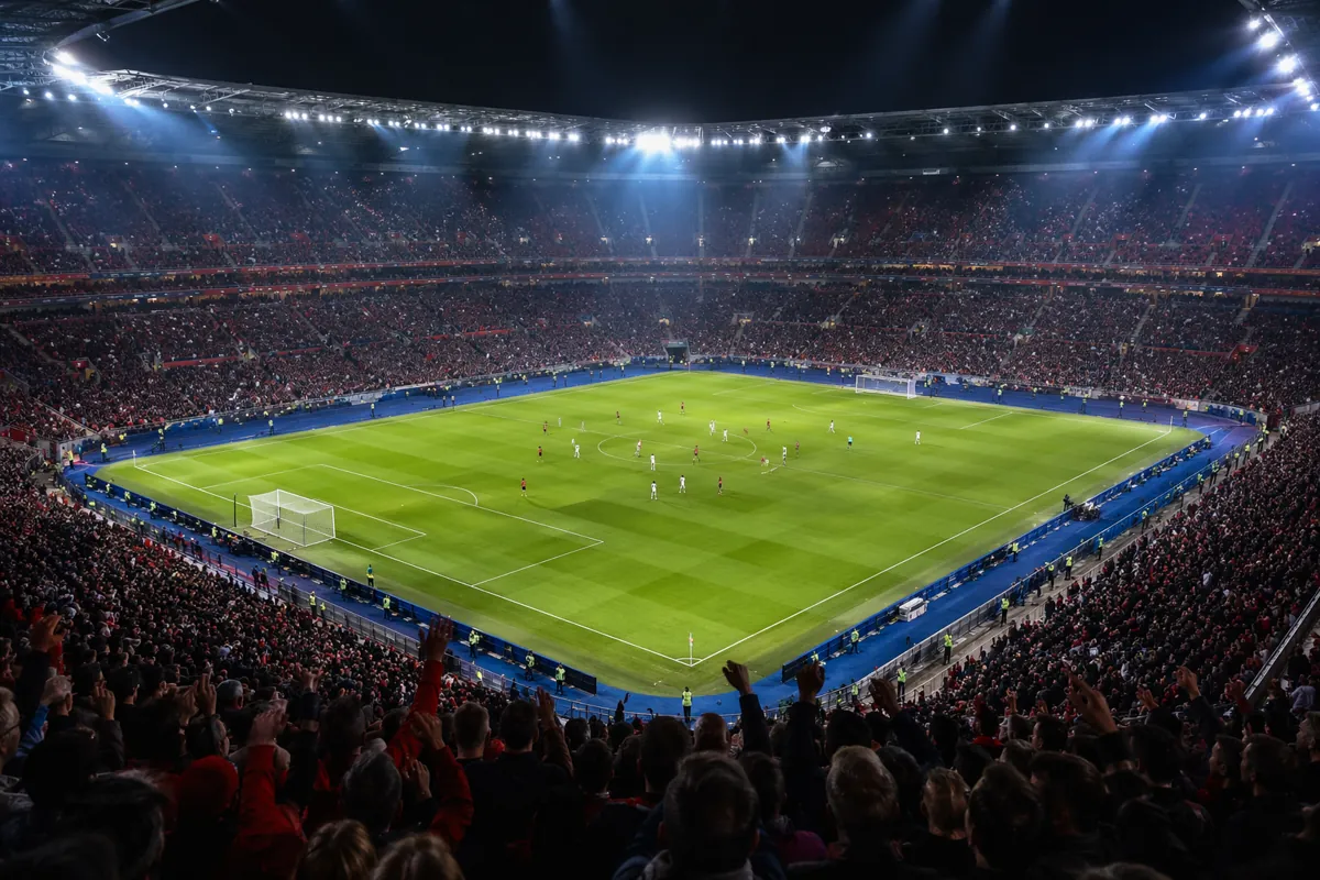 Wide shot of a professional football stadium during a knockout match, packed with cheering