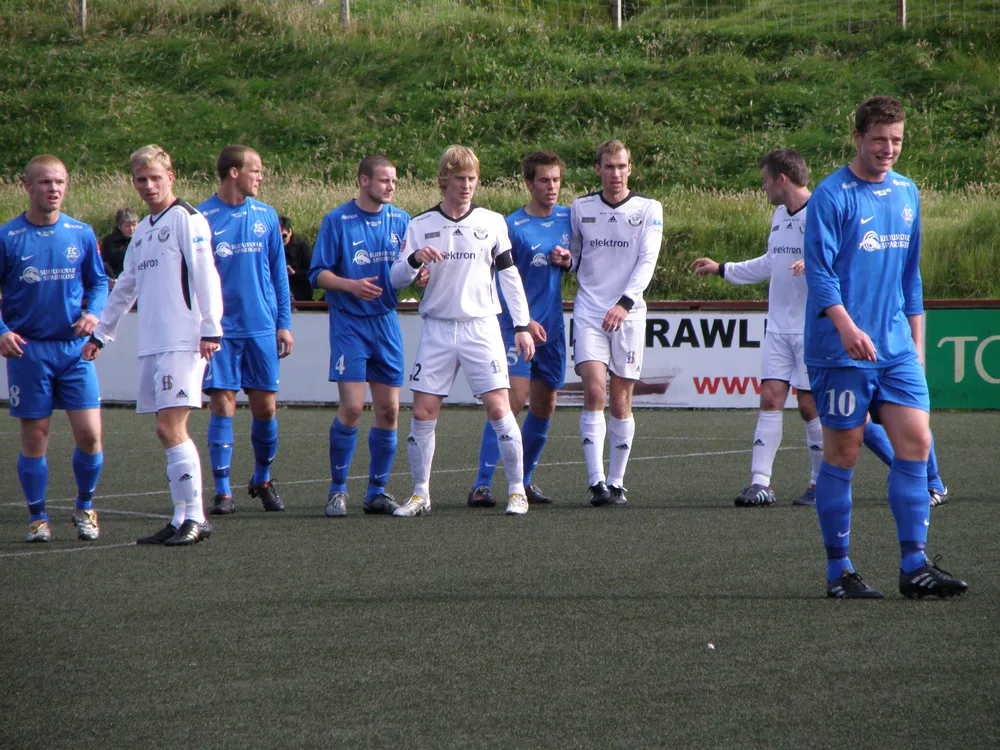Blurred shot of generic football players competing on a green pitch, bright stad