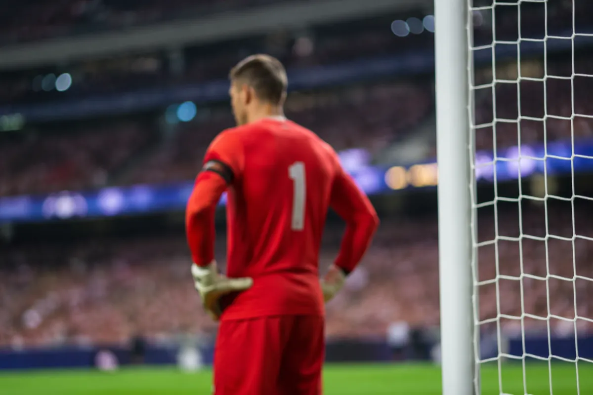 Professional sports news header image, blurred view of a soccer goalkeeper in red jersey s