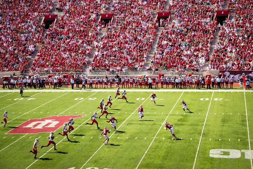 Wide shot of football stadium spectator stands full of cheering fans, vibrant at