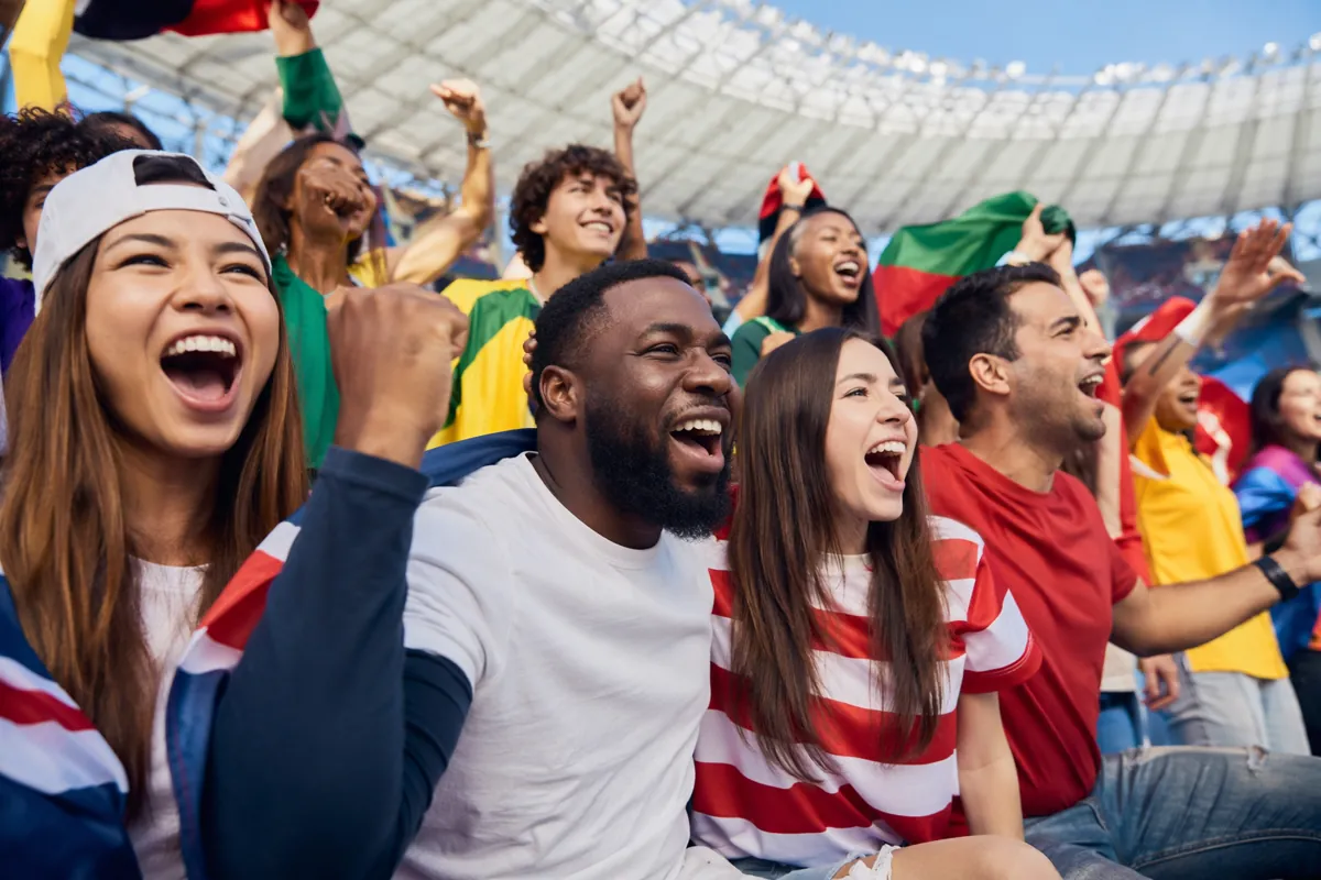 Editorial news photo of diverse football fans of different ethnicities cheering together i