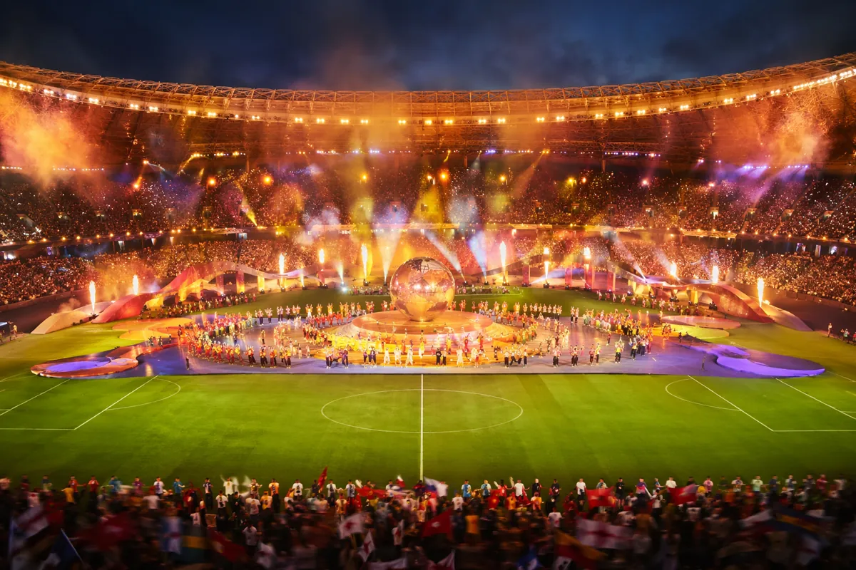 Wide shot of a vibrant World Cup opening ceremony stage inside a large soccer stadium, col