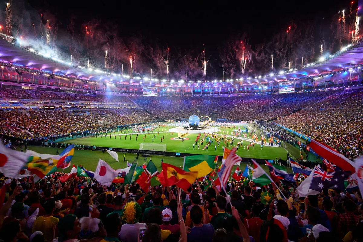 Wide shot of a vibrant FIFA World Cup opening ceremony in a packed football stadium, fans