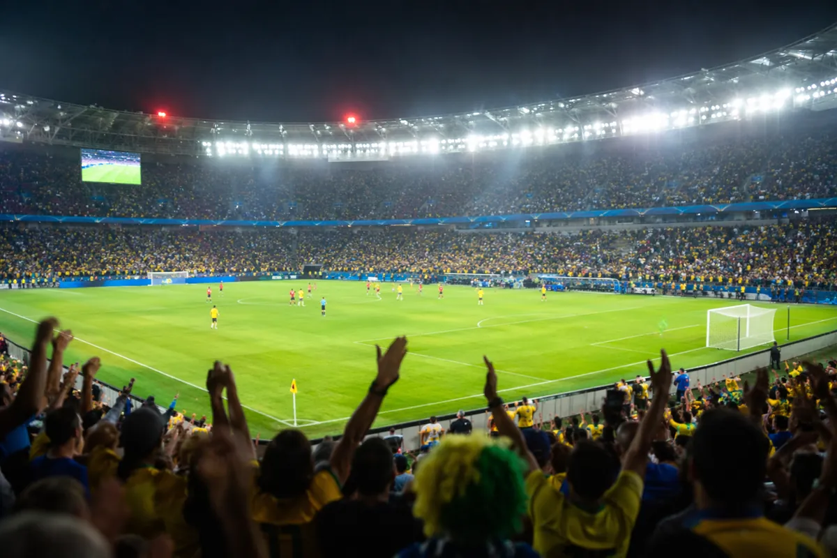 Wide shot of a professional soccer stadium during a World Cup knockout match, blurred play